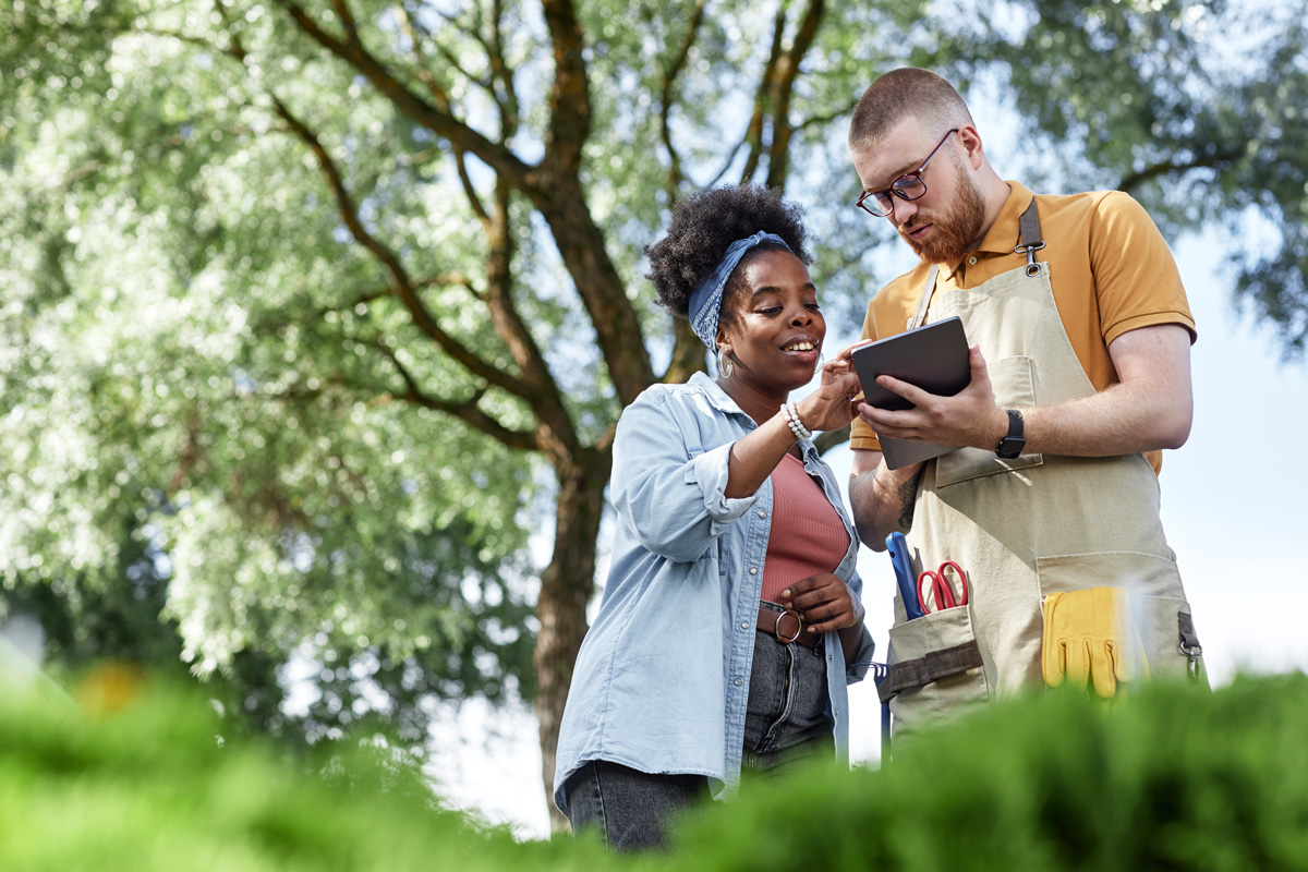 man and woman looking at work materials in a landscaping setting